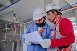 Two construction workers consult each other on how to translate safe manuals so they can improve safety in the workplace. 
