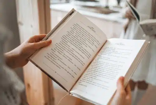 A woman's hands are holding an opened book. The is the featured image for the service page with the title, "Our Professional Translate Books in Spanish."