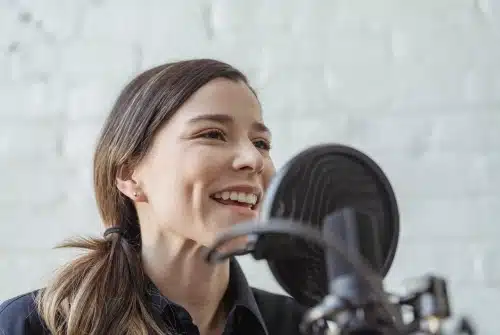 A woman speaks into a microphone as she executes Spanish voice over and narration services.